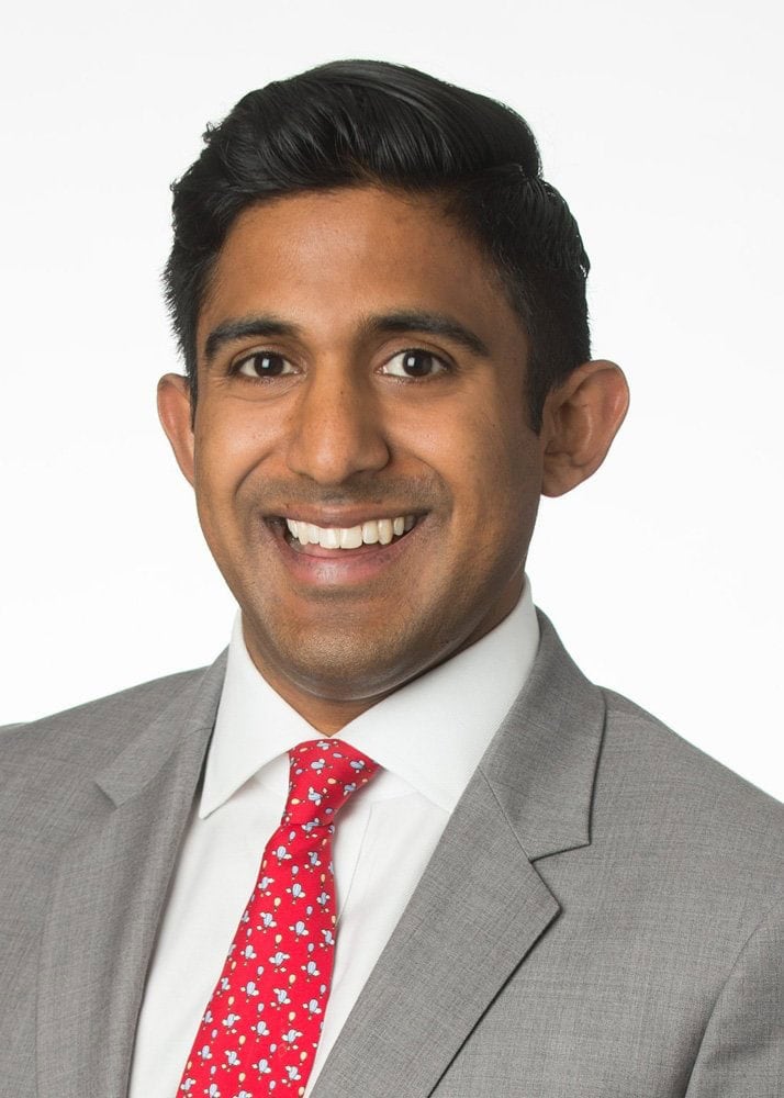 Headshot example featuring a man in a light gray suit with a broad, friendly smile captured against a clean, high-key white background.