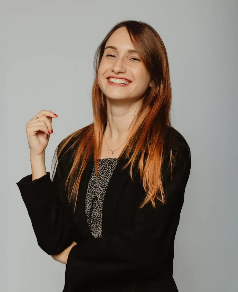 Headshot example featuring a woman with a vibrant, joyful laugh wearing a sharp black blazer over a patterned top, captured in an open and fluid pose against a neutral studio backdrop.